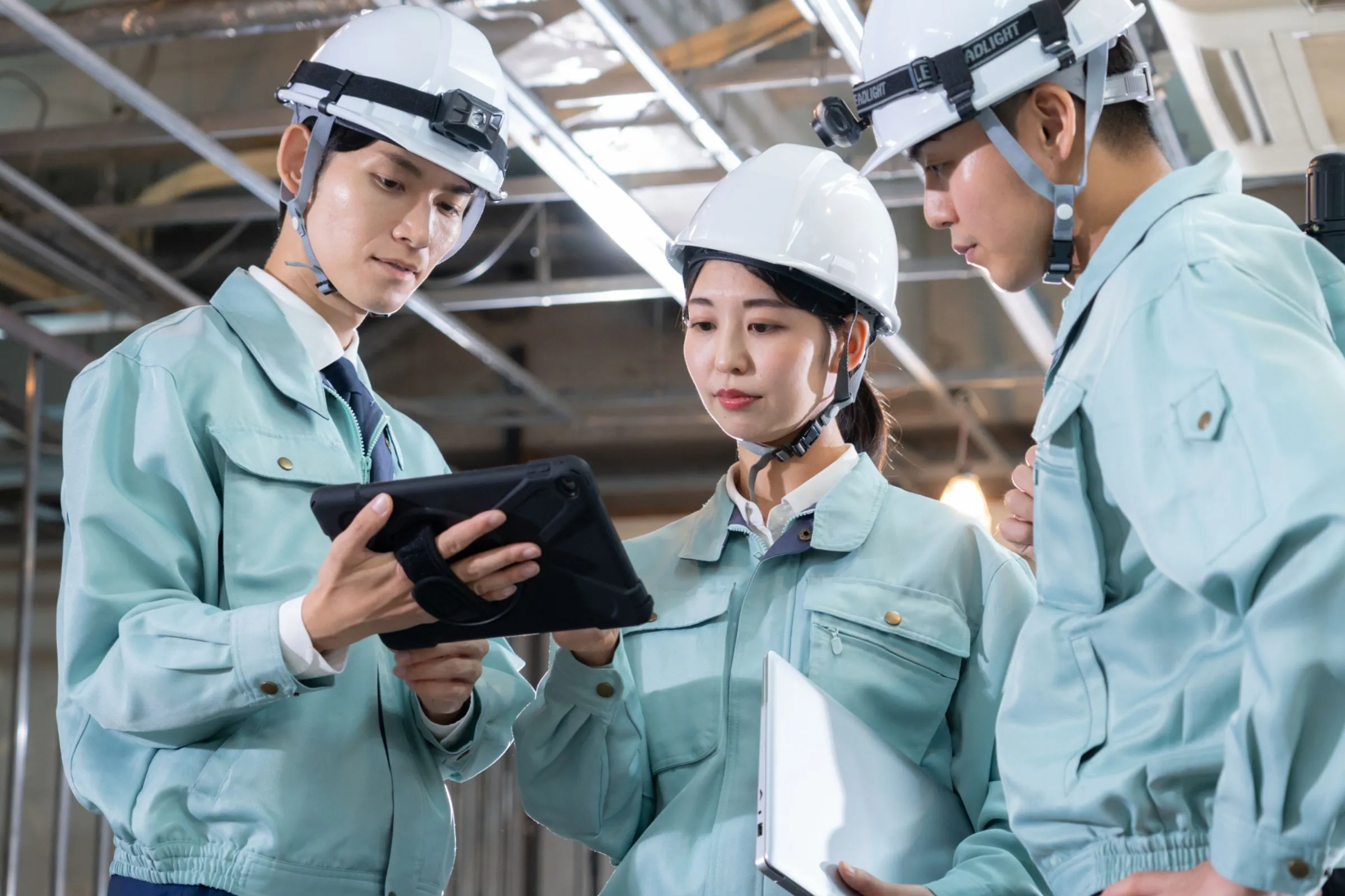 現場でタブレットを見ながら打ち合わせをする建設会社の社員。建設業の採用サイト・採用ページ制作